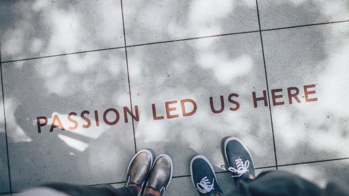 People standing on a sidewalk where Passion Led Us Here is written on the ground